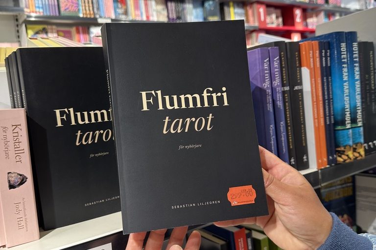 Flumfri tarot för nybörjare i handen framför bokhandelns hylla för livsåskådning.