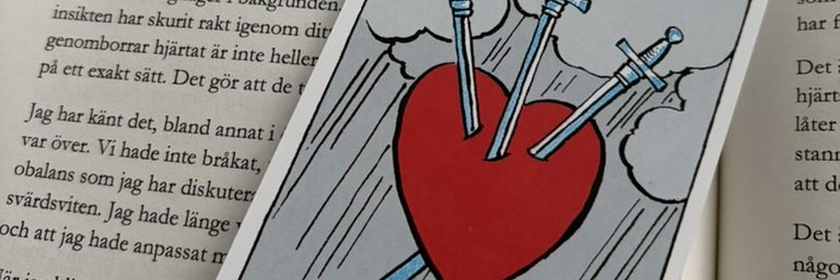 Kortet Tre Svärd lagt över bokens uppslag om Tre i svärd.